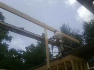 Carpenter setting a ridge beam over a new addition frame — Ice Dam Removal by Roofing Brothers in Carville