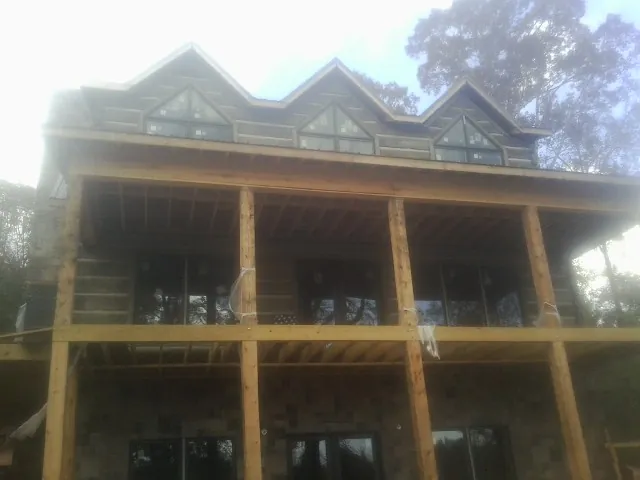 Dormers and porch framing on a large log home under construction — Roof Coating work by our crew in Carville