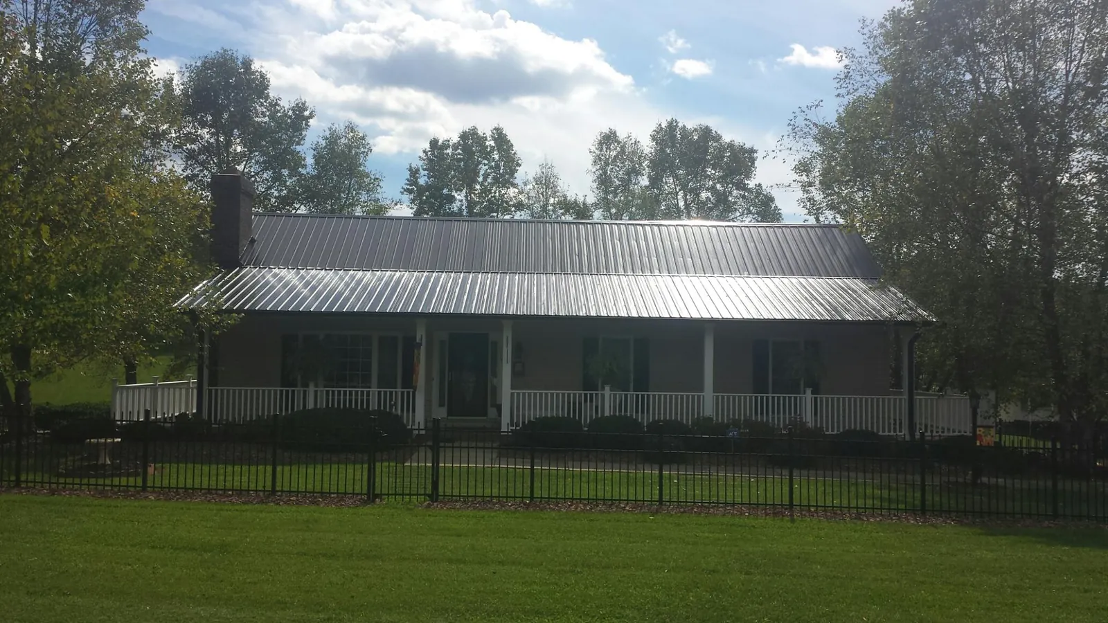 Gray metal roof on a brick ranch with a full width front porch — Gutter Guard Installation work by our crew in Carville