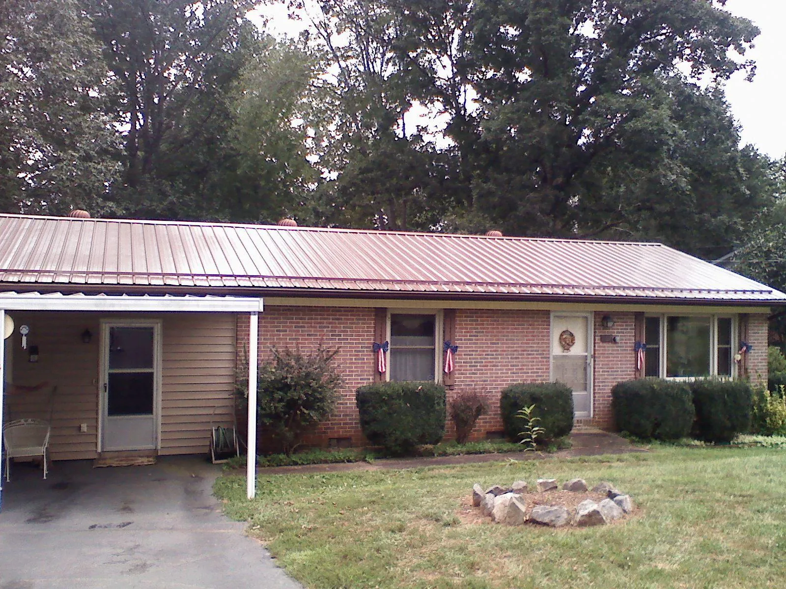 Bronze metal roof and carport on a brick ranch home — Roof Repair work by our crew in Carville