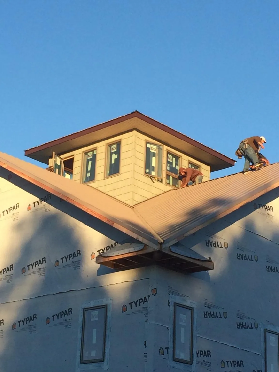 Roofers working around a rooftop cupola on a new metal roof at sunset — Roof Waterproofing in Carville by Roofing Brothers